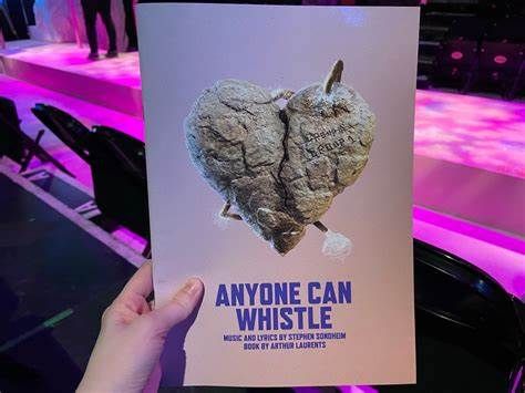 A hand holding the Anyone Can Whistle playbill